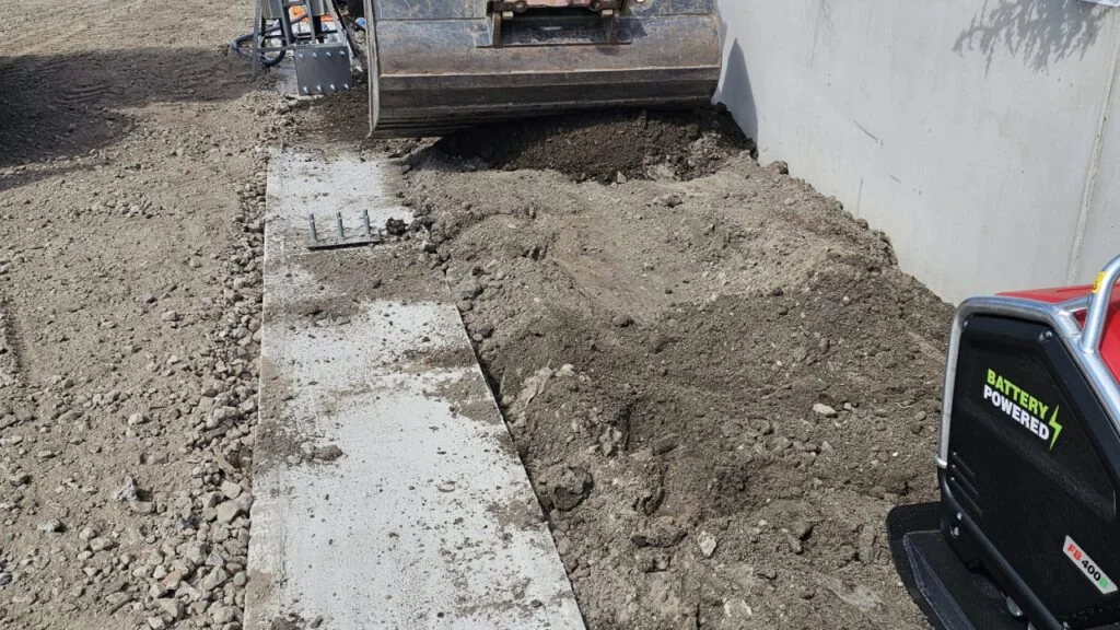 Trilplaat bij een betonnen wand en grondwerk