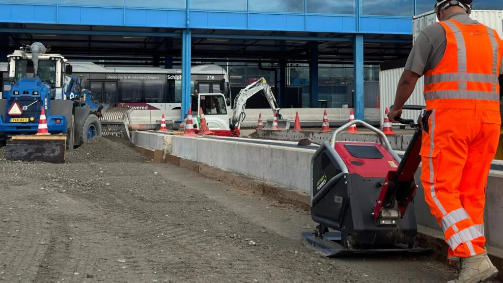 Verdichten van een zandbed langs betonranden