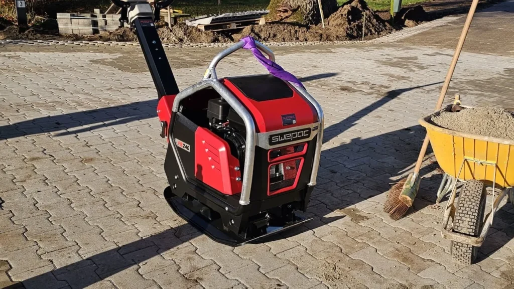 elektrische trilplaten en accu-trilstampers verdichten zand op een stadsbouwplaats met laadunit op de achtergrond