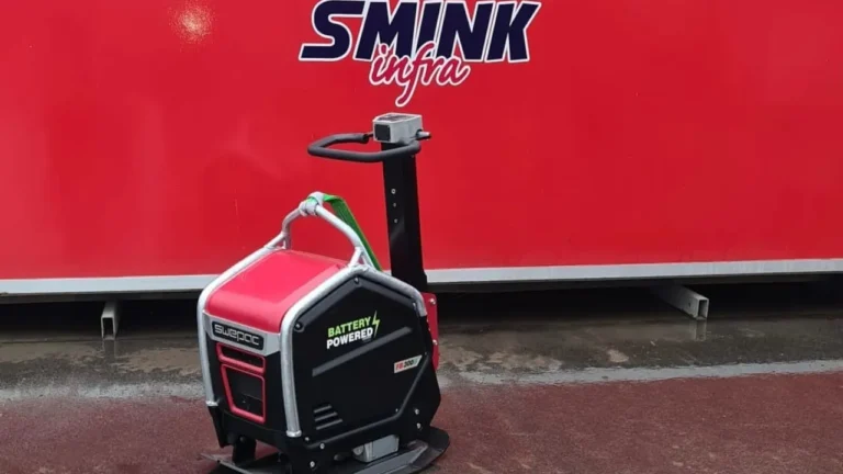 stratenmaker verdicht een smalle sleuf langs trottoir met accu trilstamper, trilplaat staat verderop op zandbed