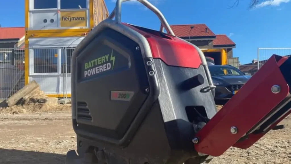 stratenmaker bedient een elektrische trilplaat op een half afgewerkte straat, met oudere trilplaten vaag op de achtergrond