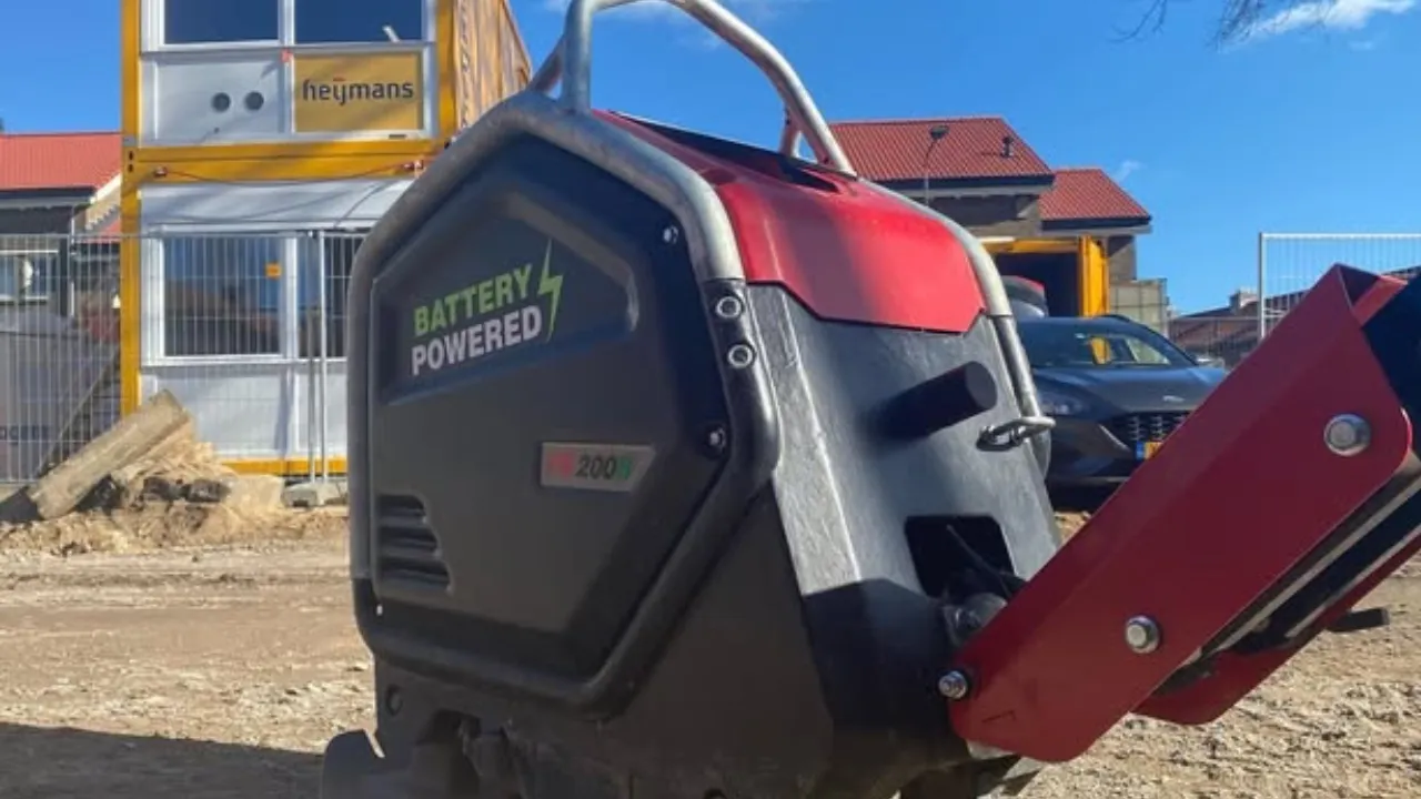 stratenmaker bedient een elektrische trilplaat op een half afgewerkte straat, met oudere trilplaten vaag op de achtergrond