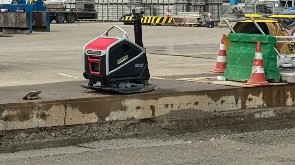 zware accu trilplaat met blauwe accupack op zandbaan tussen stoepbanden op gww-project