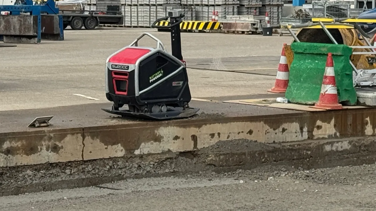 zware accu trilplaat met blauwe accupack op zandbaan tussen stoepbanden op gww-project